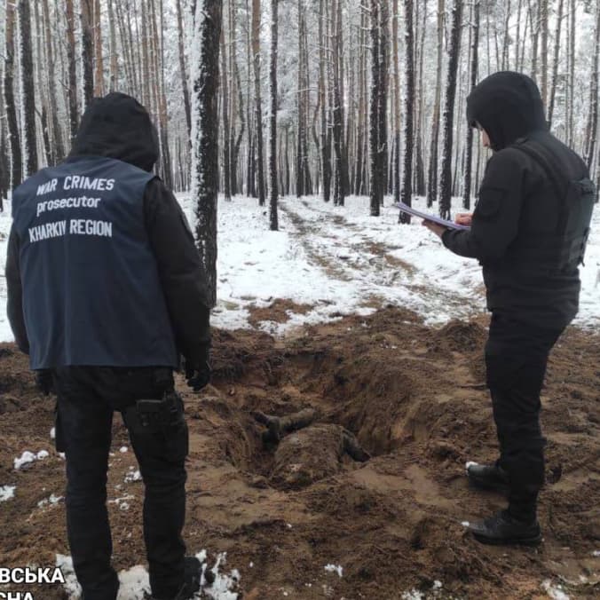 Law enforcement officers exhume the bodies of two men shot by Russian soldiers in the Kharkiv region