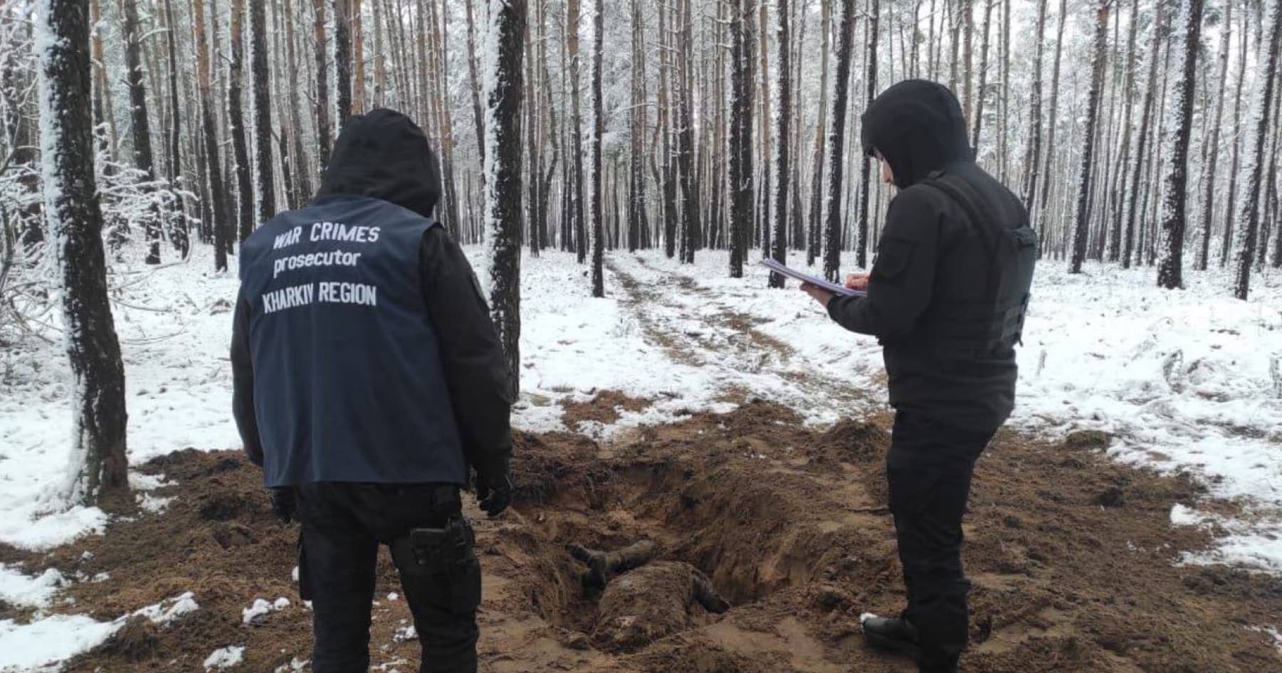 Law enforcement officers exhume the bodies of two men shot by Russian soldiers in the Kharkiv region